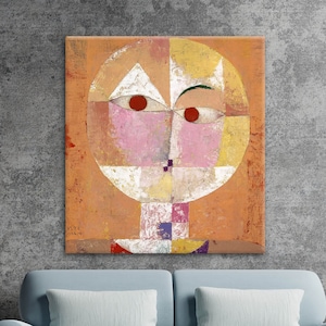 Peut inclure: Tableau d'art abstrait représentant un visage géométrique avec des yeux rouges, des joues roses et un triangle blanc. L'œuvre est encadrée dans un carré sur fond orange.