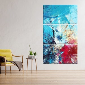 May include: Abstract art triptych in shades of blue, white, and red. The artwork is displayed on a white wall above a wooden floor. A yellow chair with a brown throw and a small side table with plants are in the foreground.