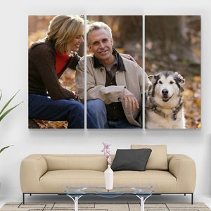 May include: A three-panel canvas print depicting a couple and a dog in a natural setting. The couple are seated, smiling, and interacting with a large dog. The background features autumn leaves, creating a warm, natural scene.
