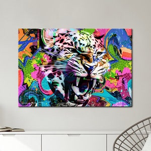 May include: A canvas art print featuring a vibrant, abstract depiction of a roaring jaguar. The artwork showcases a bold color palette with splashes of pink, green, blue, and orange, creating a dynamic and energetic composition. The jaguar's face is the focal point.