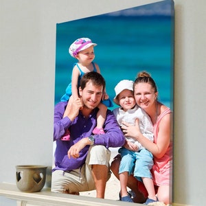 May include: A family portrait printed on canvas, depicting a man in a purple shirt, a woman in a pink top, and two children. The backdrop is a bright blue sea, creating a summery feel.