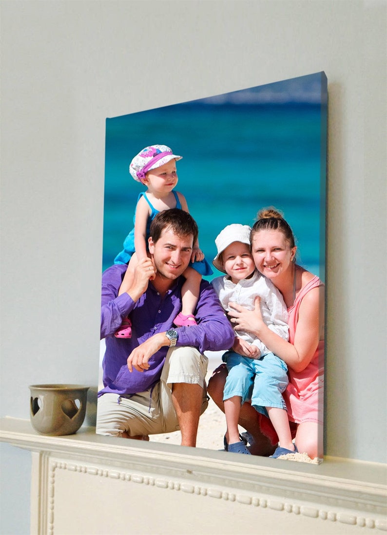 May include: A family portrait printed on canvas, depicting a man in a purple shirt, a woman in a pink top, and two children. The backdrop is a bright blue sea, creating a summery feel.