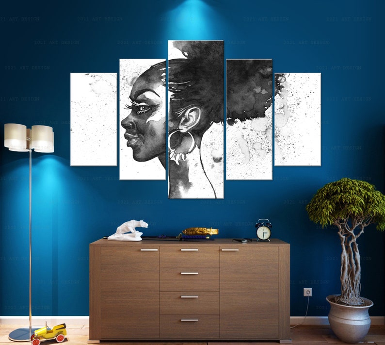 May include: A five-panel black and white artwork depicting a woman's profile. The artwork features a watercolor style with splatters and a dark background. The woman is wearing large hoop earrings. The artwork is displayed on a blue wall above a wooden cabinet.