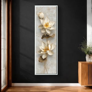 Puede incluir: Una obra de arte vertical en lienzo con tres flores de loto blancas con centros y detalles dorados, junto con hojas y tallos marrones. Las flores se encuentran sobre un fondo texturizado blanquecino, enmarcadas en un borde blanco.