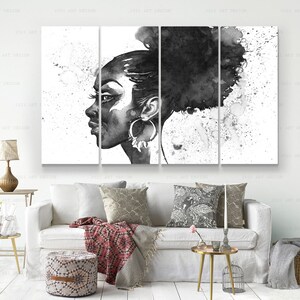 May include: Black and white watercolor artwork of a woman's profile, divided into five panels. The woman has large hoop earrings and her hair is styled in a bun. The background features paint splatters, creating an artistic effect. The artwork is displayed above a white sofa.