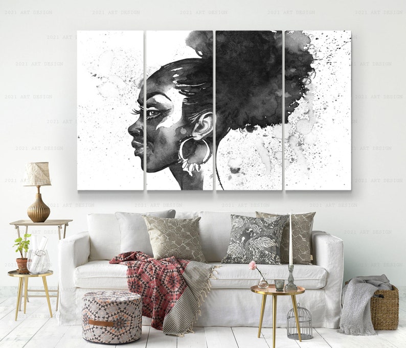 May include: Black and white watercolor artwork of a woman's profile, divided into five panels. The woman has large hoop earrings and her hair is styled in a bun. The background features paint splatters, creating an artistic effect. The artwork is displayed above a white sofa.