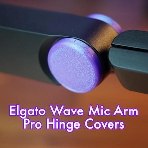 Könnte beinhalten: Lilafarbene Scharnierabdeckungen für den Elgato Wave Mic Arm Pro. Die Abdeckungen bestehen aus strukturiertem Kunststoff und sind so konzipiert, dass sie über die Scharnierpunkte des Mikrofonarms passen.