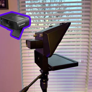 May include: Black webcam with the text "Elgato Facecam Pro" and a black video light mounted on a tripod. The webcam is rectangular with a lens and a blue light. The video light has a screen.