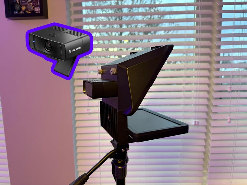 May include: Black webcam with the text "Elgato Facecam Pro" and a black video light mounted on a tripod. The webcam is rectangular with a lens and a blue light. The video light has a screen.