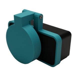 May include: A teal-colored, 3D-printed speaker accessory with a circular cover and a rectangular frame. The speaker itself is black. The cover is attached to the frame with a hinge and a screw.