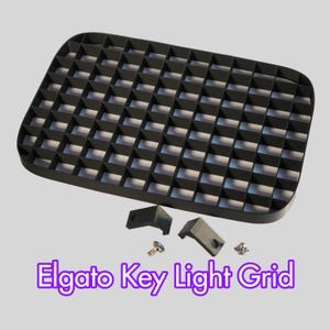 Peut inclure: Un Elgato Key Light Grid noir avec un motif quadrillé, deux supports de montage noirs et deux vis. Le texte "Elgato Key Light Grid" est affiché en violet en bas de l'image. Ce produit est conçu pour les Elgato Key Lights.