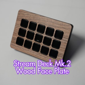 以下が含まれることがあります： 16個の黒い正方形のボタンが付いた、Stream Deck Mk.2用の長方形の木製フェイスプレート。木目は見え、テキスト「Stream Deck Mk.2 Wood Face Plate」は紫で表示されています。