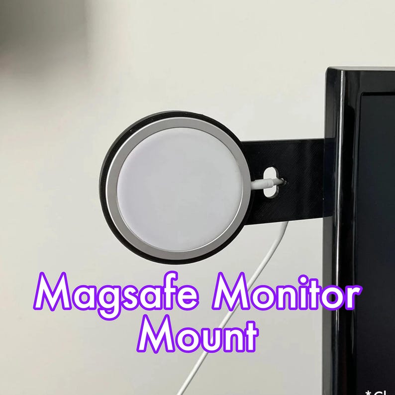 Puede incluir: Un soporte de monitor Magsafe negro y plateado fijado al lado de un monitor de computadora negro. El soporte tiene un c&iacute;rculo blanco en el centro.