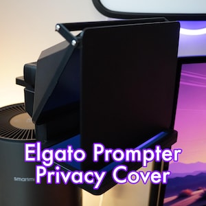 May include: Black privacy cover for an Elgato prompter. The cover is made of a rigid material and has a hinged design. The cover is designed to block the view of the prompter screen from the camera.