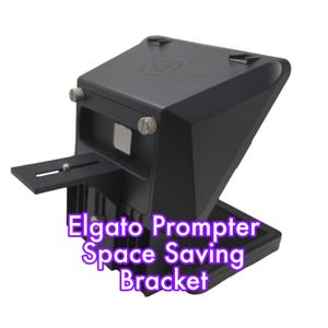Könnte beinhalten: Schwarze Elgato Prompter platzsparende Halterung. Die Halterung hat eine rechteckige Basis und eine schräge Oberseite. Sie verfügt über eine Montageplatte und verstellbare Knöpfe. Der Text "Elgato Prompter Space Saving Bracket" ist in Lila dargestellt.