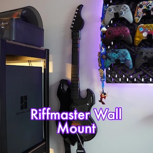 May include: A black electric guitar mounted on a wall with the text "Riffmaster Wall Mount".