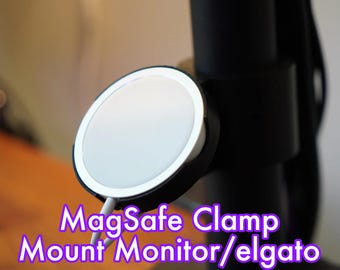 Puede incluir: Un soporte de abrazadera MagSafe blanco para un monitor o una luz elgato. La abrazadera está unida a un brazo de monitor negro.