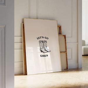 May include: A white poster with black text that reads "Let's Go Girls" and a black and white illustration of two cowboy boots.