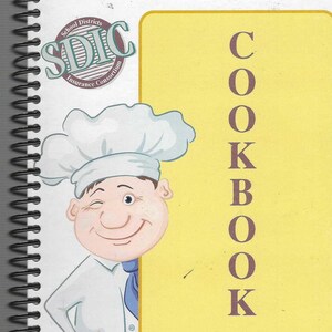 May include: A yellow cookbook with the word "COOKBOOK" written vertically in brown letters. A cartoon chef with a white chef's hat and a blue neckerchief peeks out from behind the cover. The text "School Districts SDIC Insurance Consortium" is on the cover. The text "A non-profit workers' compensation administration and claims service for public school systems since 1979." is at the bottom of the cover.