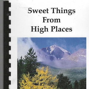 May include: A cookbook titled "Sweet Things From High Places" with a photo of a mountain peak with snow on top and autumn foliage in the foreground. The text "Autumn-Tahosa Valley ©James Frank" is at the bottom of the photo. The text "A Collection of Recipes Inspired by the Grandeur of Rocky Mountain National Park" is below the photo.