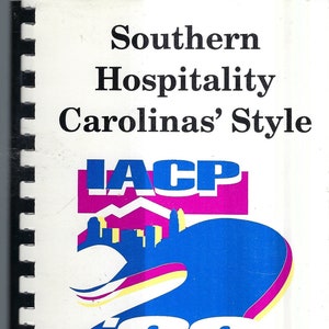 Op de afbeelding: Een wit boekje met een blauw en roze logo met de tekst "IACP 99 CHARLOTTE" en de tekst "Southern Hospitality Carolinas' Style" bovenaan. Het boekje bevat ook de data "October 30 - November 4, 1999" en de locatie "Charlotte, North Carolina".
