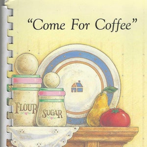 Peut inclure: Une couverture de livre de cuisine avec un fond jaune et une illustration peinte à la main d'une étagère de cuisine avec une assiette, une poire, une tomate et deux bocaux étiquetés "Farine" et "Sucre". Le texte "Come For Coffee" est en haut de la couverture et le texte "Favorite Recipes of the Klassen Family Crooked Creek, Alberta" est en bas.