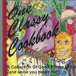 May include: A colorful cookbook cover with a collection of cartoon vegetables, including a purple eggplant, a yellow carrot, a red tomato, a green onion, and a white onion. The text on the cover reads "One Classy Cookbook" and "A Collection Of Good Things to Eat (and some you better not!)".