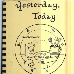 May include: A yellow cookbook with a black and white illustration of a pie, rolling pin, flour bag, and kitchen utensils on a plate. The title of the cookbook is "Yesterday, Today with love".