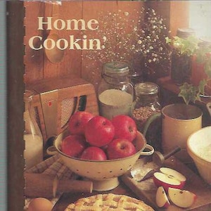 Puede incluir: Un libro de cocina vintage titulado "Home Cookin': Southern Saratoga PWP" con una foto de un pastel y manzanas en la portada.