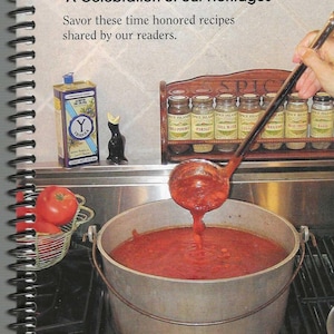 Op de afbeelding: Afbeelding van een kookboekcover met de titel "THE MELTING POT" en de tekst "A Celebration of our Heritages". Een pollepel giet tomatensaus in een grote pot. Kruiden en olijfolie zijn zichtbaar.