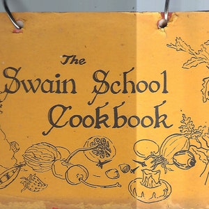 Puede incluir: La portada del libro de cocina de la Swain School presenta un fondo amarillo con texto negro e ilustraciones. El título está escrito en una fuente de letra cursiva decorativa. Las ilustraciones incluyen verduras, frutas y otros alimentos.