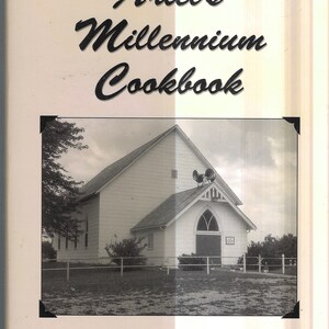 May include: A black and white photo of a white church building with a sign that reads "Ariel Christian Church". The church has a steeple with a bell on top. The photo is from the Ariel's Millennium Cookbook.