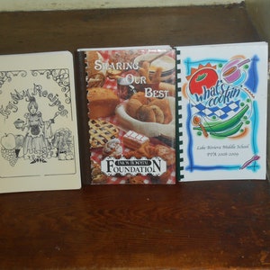 May include: Three spiral bound cookbooks with colorful covers. The first cookbook is titled "Try My Recipes" and features a cartoon woman holding a pot and a spoon. The second cookbook is titled "Sharing Our Best" and features a variety of baked goods. The third cookbook is titled "What's Cookin'" and features a red tomato, green beans, and a blue and white checkered pattern.