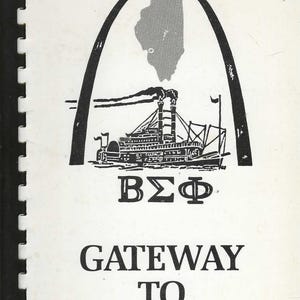May include: Black and white illustration of a steamboat under an arch with the outline of Illinois. The text reads "BΣΦ" and "Gateway to Good Eating" on a white background. The image is bound with a black spine.