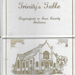 May include: White rectangular item with gold text and a gold outline. The text reads "Trinity's Table" and "Logansport in bass county Indiana". A gold illustration of Trinity Lutheran Church is at the bottom.