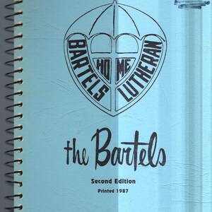 May include: A blue spiral bound notebook with a black and white logo of an umbrella with the words "Bartels Lutheran Home" around it. The text "the Bartels" is written in black cursive script below the logo. The text "Second Edition Printed 1987" is printed in black below the cursive text.