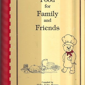 May include: A yellow cookbook with the title "Food for Family and Friends" in black text. The cover features a cartoon chef bear wearing a red and white chef's hat and a red and white checkered scarf. The bear is holding a wooden spoon. The cookbook is compiled by Alpha Delta Kappa Louisiana Lambda.