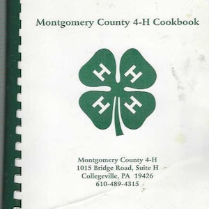 May include: A white cookbook with a green 4-H clover logo and the text "Montgomery County 4-H Cookbook". The cover also includes the organization's contact information: "Montgomery County 4-H, 1015 Bridge Road, Suite H, Collegeville, PA 19426, 610-489-4315".