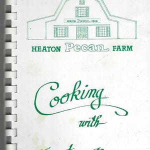 May include: A spiral-bound cookbook cover with a green line drawing of a barn and the words "Heaton Pecan Farm." Below, in cursive, it reads "Cooking with Heaton Pecans."