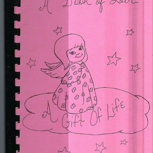 May include: A pink book with a spiral binding. The cover features a black and white illustration of an angel with wings, standing on a cloud. The text "A Book of Love" and "A Gift of Life" are written on the cover.
