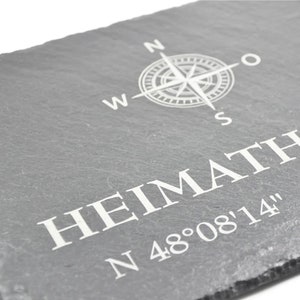 May include: A gray slate sign with a compass rose and the text "HEIMATH N 48&deg;08'14" in white.