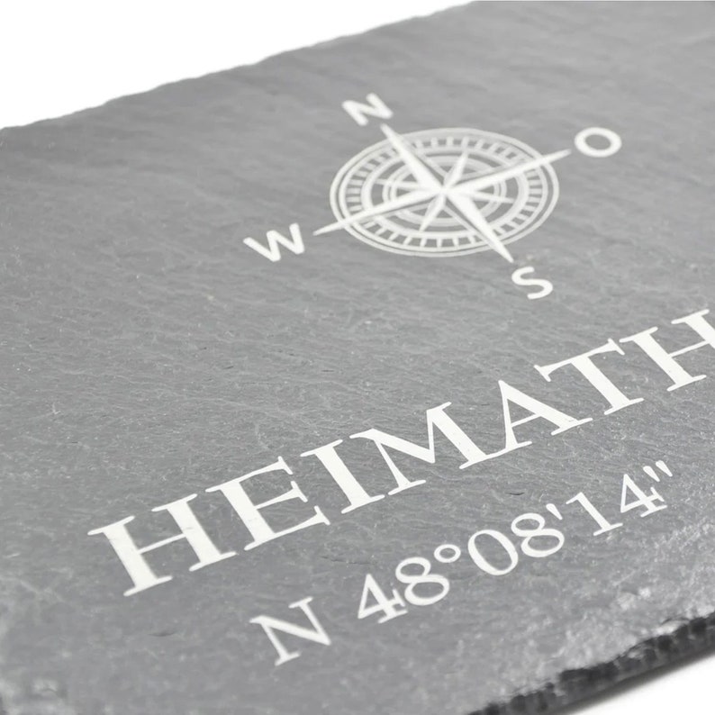 May include: A gray slate sign with a compass rose and the text "HEIMATH N 48&deg;08'14" in white.