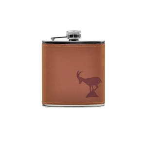 Könnte beinhalten: Eine braune, lederbezogene Trinkflasche mit silbernem Verschluss und einer roten Silhouette einer Steinbock auf der Vorderseite.