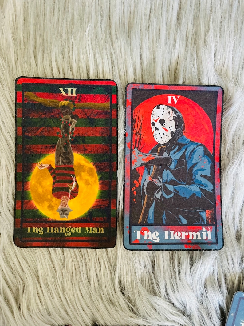 May include: Two tarot cards featuring horror movie characters. One card shows Freddy Krueger as The Hanged Man, the other shows Jason Voorhees as The Hermit. The cards have a red, black, and green color scheme.