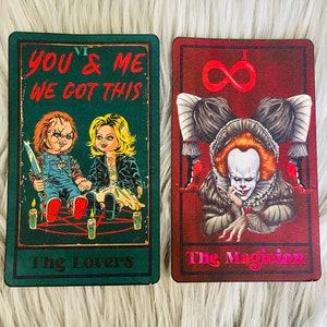 May include: Two tarot cards featuring horror movie characters. One card is green with the text "YOU & ME WE GOT THIS" and images of Chucky and Tiffany. The other card is red with the text "The Magician" and an image of Pennywise.