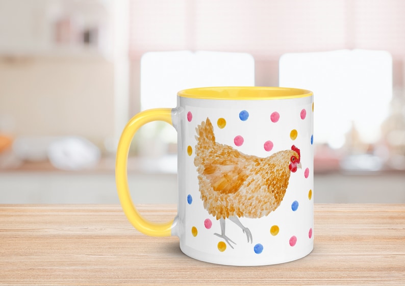 May include: A white ceramic mug with a yellow rim and handle. The mug features a watercolor illustration of a brown chicken with a red comb and wattle, standing on a white background with colorful polka dots.