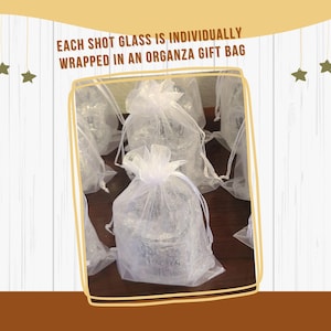 Op de afbeelding: Meerdere doorzichtige borrelglaasjes, elk afzonderlijk verpakt in een wit, halfdoorzichtig organza cadeauzakje met trekkoord. De tekst bovenaan luidt: EACH SHOT GLASS IS INDIVIDUALLY WRAPPED IN AN ORGANZA GIFT BAG.