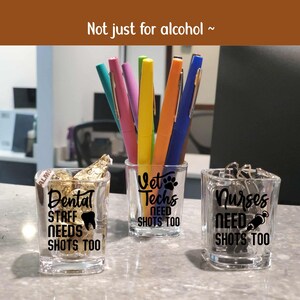 Op de afbeelding: Drie doorzichtige vierkante shotglaasjes met zwarte tekst. De eerste toont Dental Staff Needs Shots Too met een tand-icoon. De tweede toont Vet Techs Need Shots Too met een pootafdruk. De derde toont Nurses Need Shots Too met een spuit-icoon.