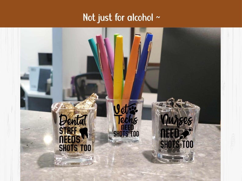 Op de afbeelding: Drie doorzichtige vierkante shotglaasjes met zwarte tekst. De eerste toont Dental Staff Needs Shots Too met een tand-icoon. De tweede toont Vet Techs Need Shots Too met een pootafdruk. De derde toont Nurses Need Shots Too met een spuit-icoon.