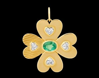 Puede incluir: Un colgante de oro con forma de trébol de cuatro hojas con una piedra preciosa de esmeralda verde en el centro y pequeños diamantes en cada una de las cuatro hojas en forma de corazón.
